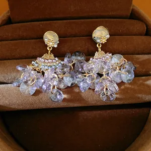 Detailed macro view of elegant fan-shaped earrings with lavender faceted glass tassels.