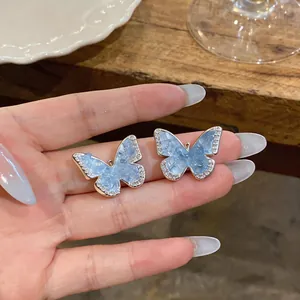 Macro view of blue gradient butterfly ear clips with sparkling zircon borders.