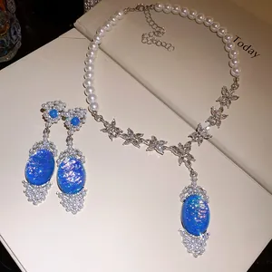 Close-up of elegant pearl necklace and earrings set with oval blue opal pendants