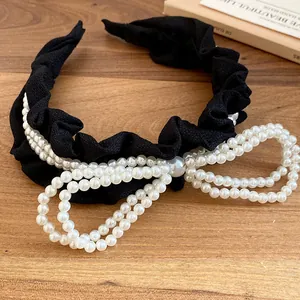 Detail view of black pleated headband with elegant multi-strand pearl bow decoration