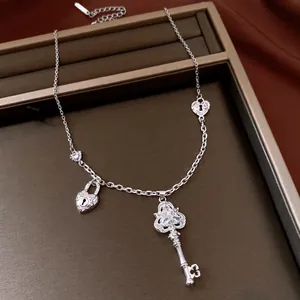 Close-up of a silver-toned necklace featuring an ornate zircon key and heart lock pendants.
