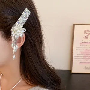 Close-up of elegant pearl flower hair clip with rhinestone tassels on brunette hair