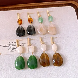 Nahaufnahme von Vintage-Resin-Ohrringen in verschiedenen Erdtönen auf strukturiertem Leinen.