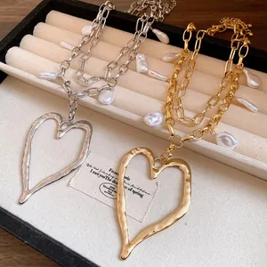 Detailed macro view of baroque pearl and large heart pendant necklace in gold and silver.