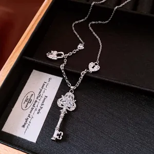 Close-up detail of silver vintage key necklace with zircon-encrusted heart lock charms
