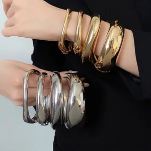 Set di bracciali aperti dorati e argentati lisci e irregolari sui polsi della modella