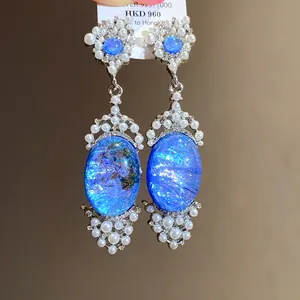 Intricate close-up of vintage blue stone earrings with pearl and rhinestone halo