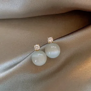 Close-up view of elegant cat's eye stone stud earrings with round sparkling zircon accents
