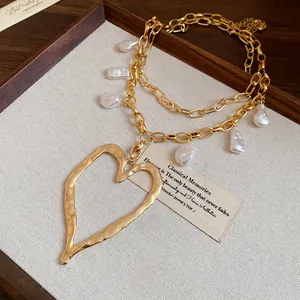 Detailed close-up of retro gold double-layer necklace with pearls and large heart pendant.