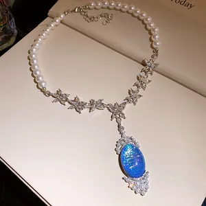 Close-up of elegant pearl necklace with crystal flowers and blue oval opal-like pendant.