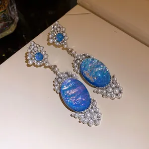 Detailed view of luxury oval blue stone earrings with pearl and crystal beads