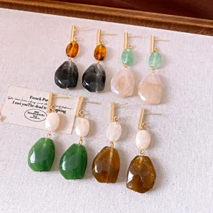 Nahaufnahme von Vintage-Harz-Ohrringen in verschiedenen Erdtönen mit Goldakzenten.