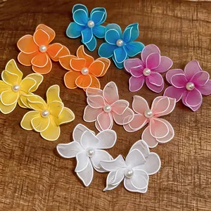 Detail view of colorful mesh flower earrings with central pearls on a wooden surface