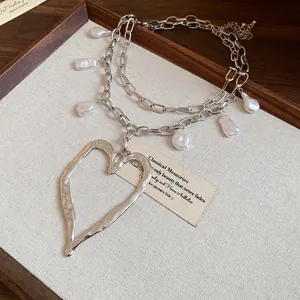 Close-up of vintage silver double-layer necklace with baroque pearls and heart pendant.