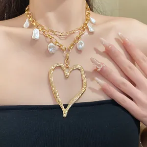 Close-up of a luxury gold chain necklace with pearls and a large open heart pendant