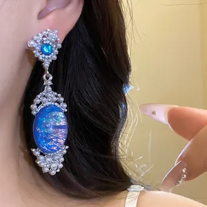 Close-up of vintage blue oval opal earrings with pearl and crystal embellishments