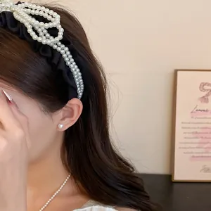 Close-up of elegant black headband with pearl bow design and matching pearl earring