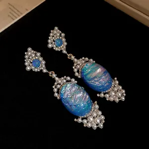 Macro shot of elegant oval blue iridescent drop earrings with pearl and crystal details