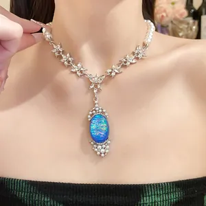 Detail of a luxury pearl necklace featuring a vibrant blue oval pendant with floral diamond links.