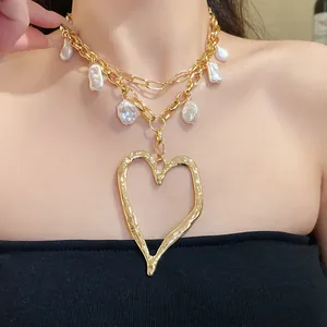 Close-up of vintage gold layered necklace with irregular pearls and large heart pendant