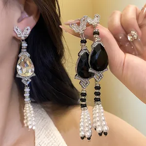 Close-up of elegant teardrop rhinestone earrings featuring long pearl tassels