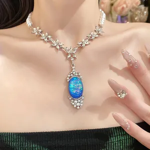 Close-up of elegant pearl and rhinestone necklace with a blue iridescent oval pendant