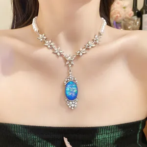 Detail showing an elegant pearl necklace with a blue oval pendant and crystal accents.