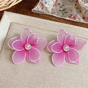 Detailed macro view of pink mesh flower earrings with elegant central white pearls.