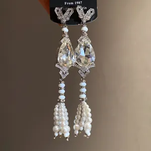 Close-up of elegant teardrop earrings with pearl tassels and shimmering crystals.