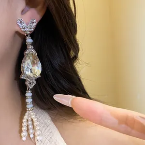 Close-up detail of rhinestone water-drop earrings with elegant white pearl tassels