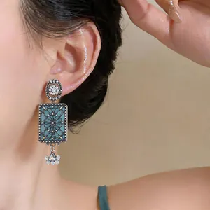 Primo piano di orecchini rettangolari blu in stile palazzo retrò con strass su modella.