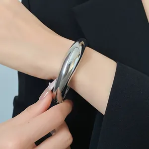Primo piano di un bracciale rigido argento irregolare indossato con un blazer nero