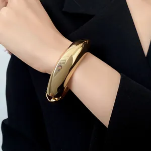Primo piano di un bracciale rigido dorato irregolare con finitura lucida effetto specchio