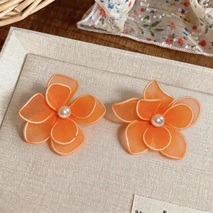 Detailed view of orange silk mesh flower earrings featuring elegant pearl centers