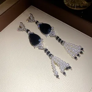 Detailed view of vintage pearl tassel earrings with black teardrop stones and crystals