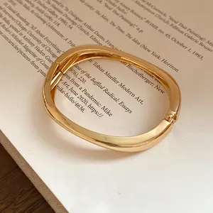 Vista ravvicinata di un bracciale rigido dorato lucido irregolare su un libro d'epoca