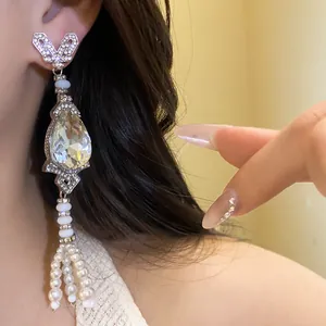 Close-up of elegant silver-tone earring with teardrop crystal and pearl tassels
