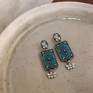 Dettaglio ravvicinato di orecchini rettangolari vintage con smalto blu e strass