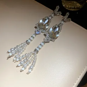 Close-up of elegant waterdrop crystal and pearl tassel earrings with silver needles