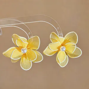 Detailed macro shot of yellow mesh flower earrings with elegant pearl centers