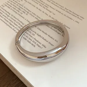 Dettaglio di un bracciale rigido argento liscio e irregolare con finitura lucida