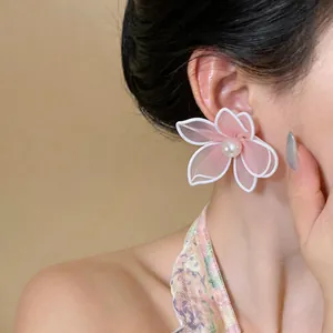 Detailed view of elegant pink mesh flower stud earrings with a center pearl on model's ear.