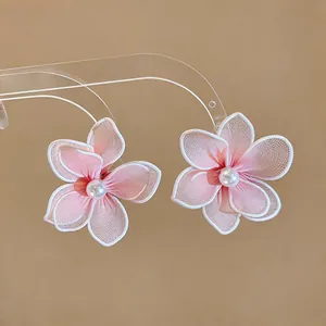 Detail view of sweet pink mesh flower earrings featuring an elegant central white pearl