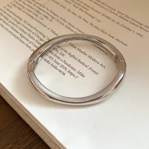 Primo piano di un bracciale rigido argento irregolare su sfondo vintage
