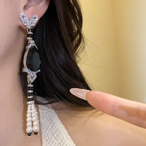 Detail shot of a vintage-style dangling earring with black teardrop stone and pearl tassels.