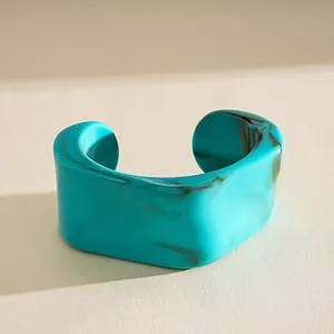 Macro detail of a turquoise acrylic cuff bracelet featuring a brown marble texture