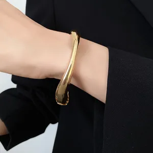 Dettaglio ravvicinato di un bracciale rigido dorato liscio e irregolare al polso