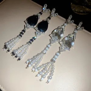 Close-up of elegant rhinestone water drop earrings with white pearl tassels