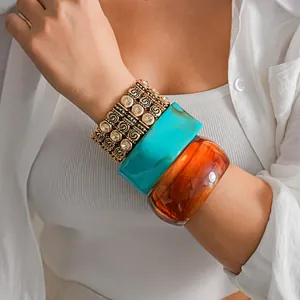 Detailed view of stacked vintage gold stretch bracelet and colorful acrylic bangles on wrist