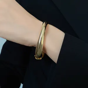 Vista dettagliata di un bracciale rigido d'oro lucido irregolare sul polso di una modella